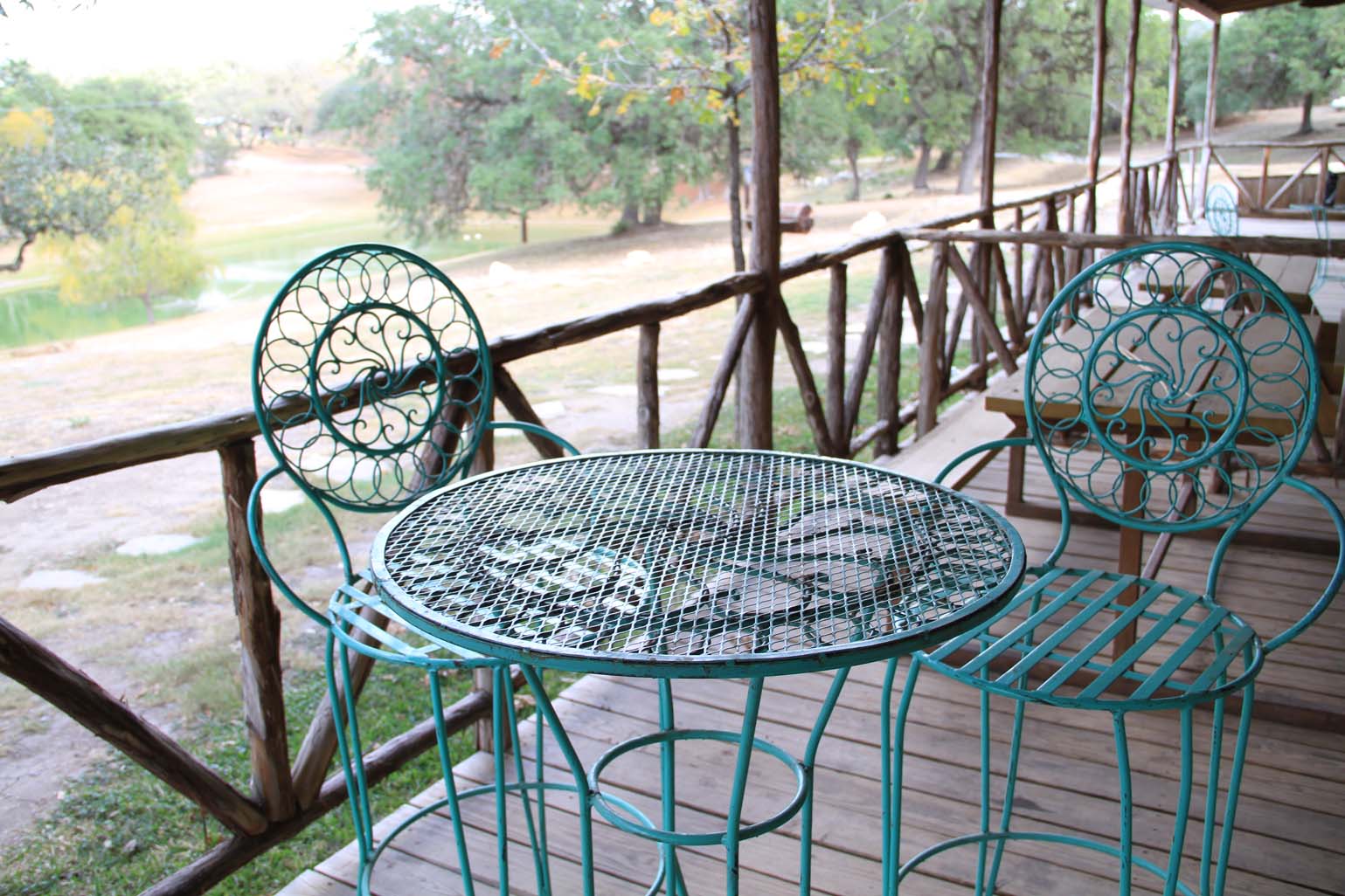 A table and chairs on the porch of an outdoor restaurant.