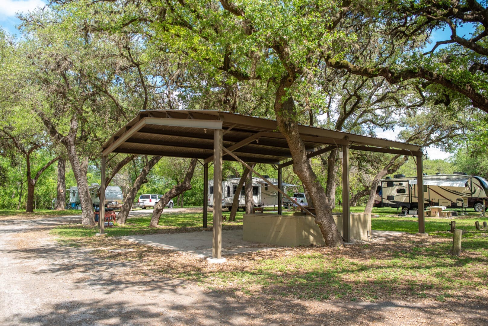 A covered area with trees and a truck parked in the background.