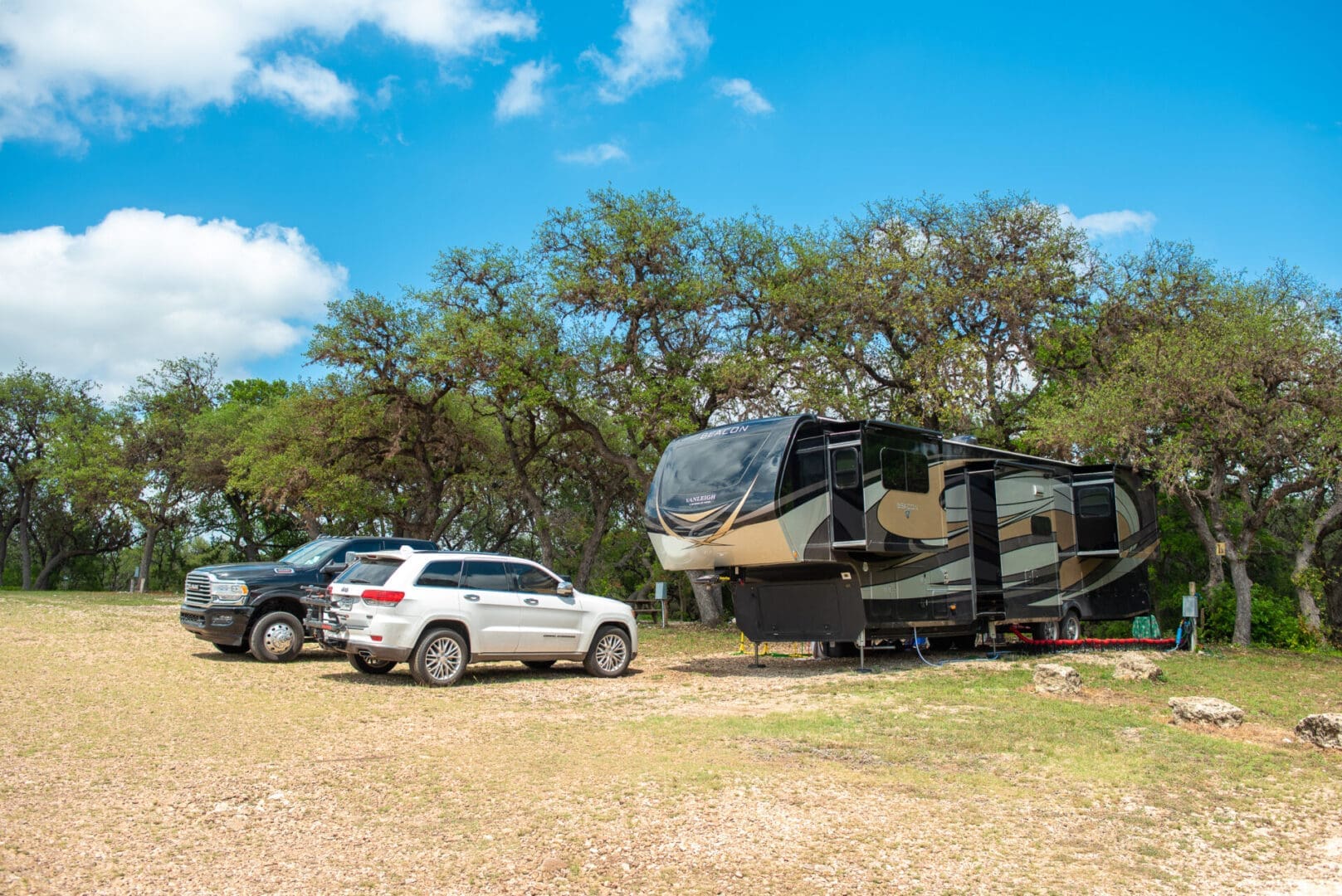 A group of cars parked in front of a large rv.