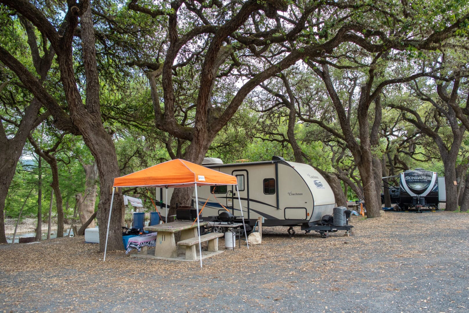 A camper with an orange tent in the woods.