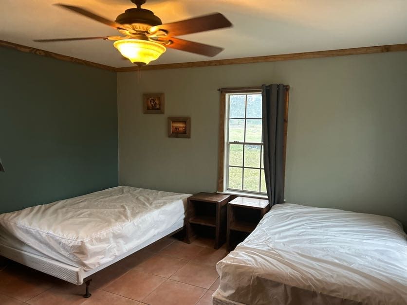 A bedroom with two beds and a ceiling fan.