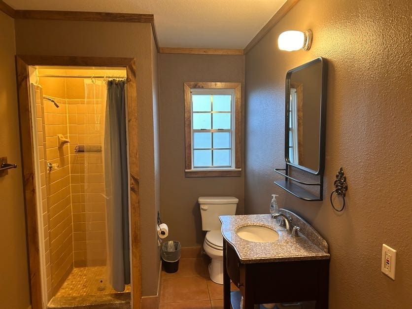 A bathroom with a toilet, sink and shower.