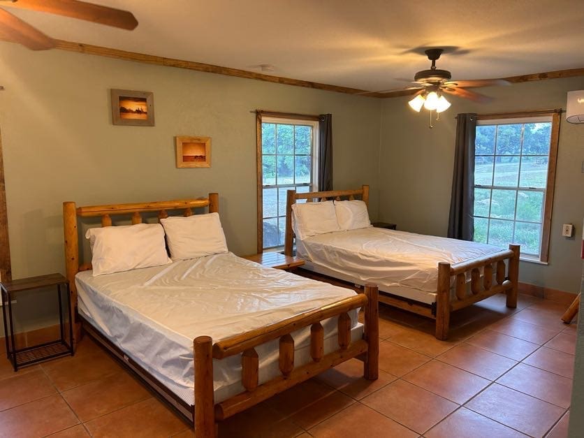 Two beds in a room with a ceiling fan.