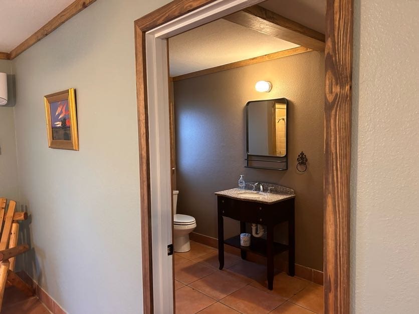 A bathroom with a sink, toilet and mirror.