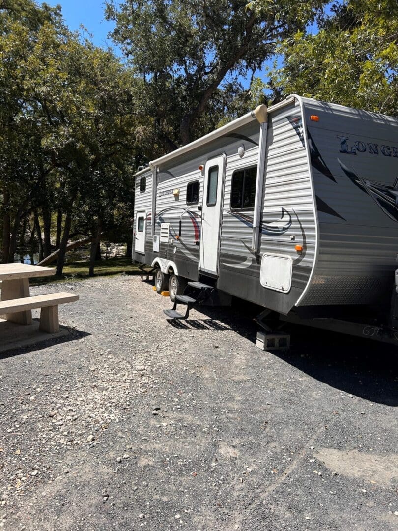 A recreational vehicle parked at a campsite with a picnic table and trees in the background.