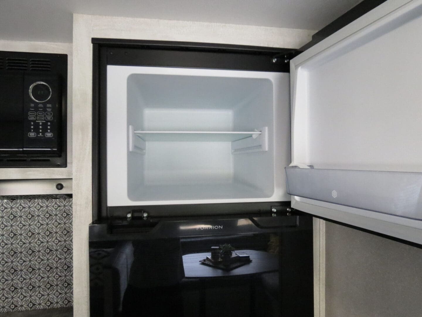 Open microwave mounted above a countertop in a kitchen with a modern design, showcasing a clean, empty interior.