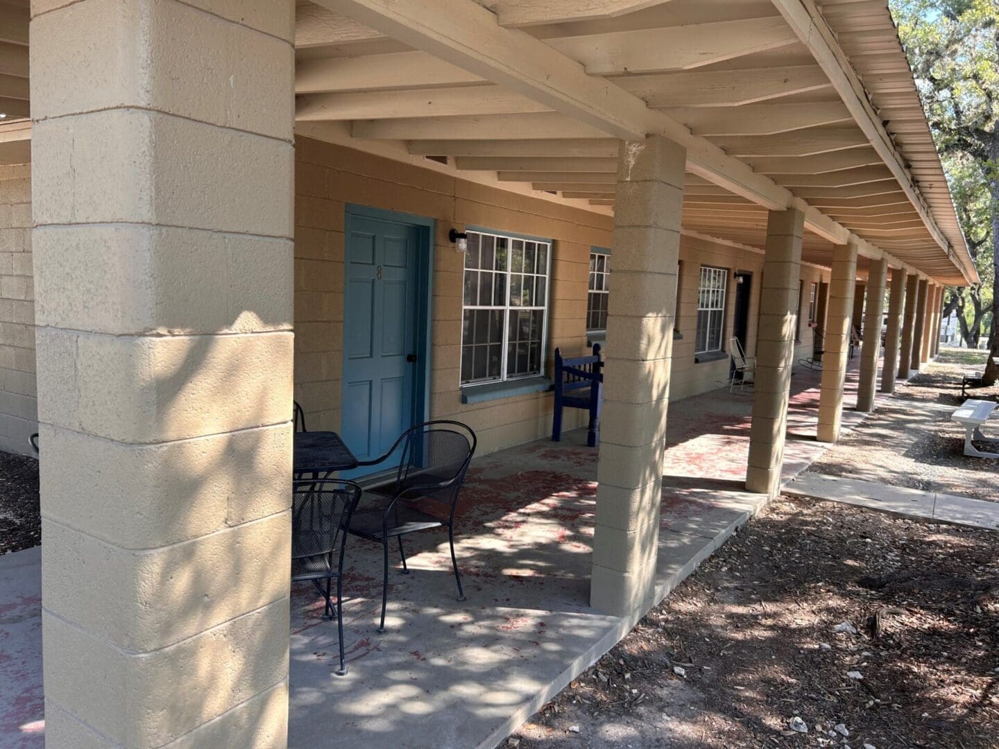 Covered porch with chairs and a door.