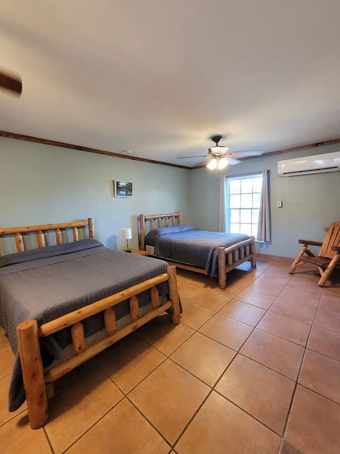 Two beds in a hotel room with tile floor.